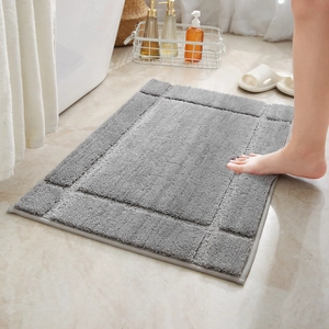 Thick grey absorbent bathroom mat with geometric border on marble floor