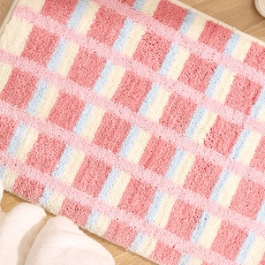 Tapis de bain damier rose et bleu en peluche douce sur un sol en bois clair moderne
