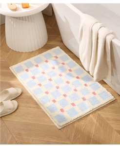 Detail of blue and white checkered bath mat with pink polka dots on wooden floor