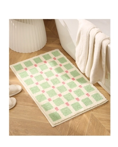 Close-up of checkered bath mat featuring plush tufted texture and soft mint green colors