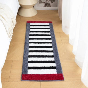Modern plush bedside rug with black white stripes and red accents in minimalist bedroom