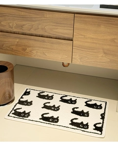 Close-up of fluffy white bathroom mat with cute black cat pattern and thick plush texture