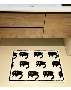 Close-up of thick flocked bathroom mat featuring a repeating black cat pattern on white