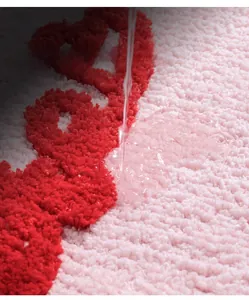 Dettaglio macro delle fibre assorbenti su un tappeto da bagno in peluche rosso e bianco