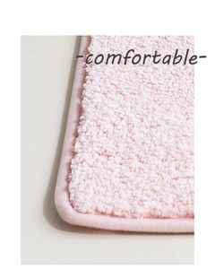 Dettaglio del tappetino da bagno rosa in pile sherpa con trama soffice e bordi cuciti