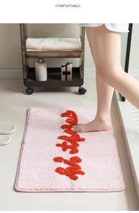 Dettaglio del tappeto da bagno rosa floccato con calligrafia rossa e texture soffice