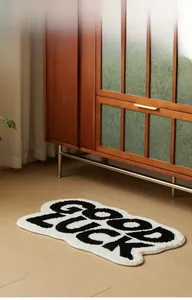 Detail of soft wave-shaped 'GOOD LUCK' bath mat on light wood floor in a cozy room