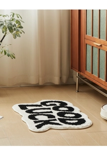Detailed plush texture of a cloud-shaped Good Luck bath mat on a wooden floor