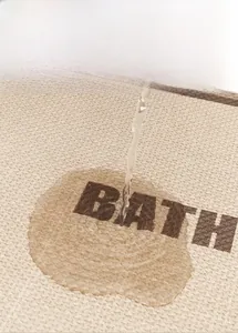 Detail of absorbent beige linen bath mat showing rapid water absorption performance