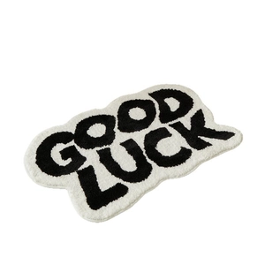 Black and white cloud-shaped GOOD LUCK absorbent bath mat with tufted texture