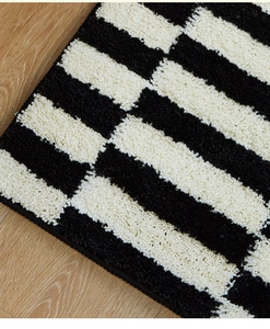 Close-up of thick black and white striped plush rug texture on light wooden floor