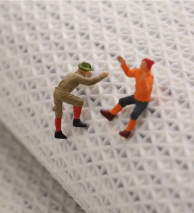 Macro view of miniature climber figures in orange and khaki on white textured surface