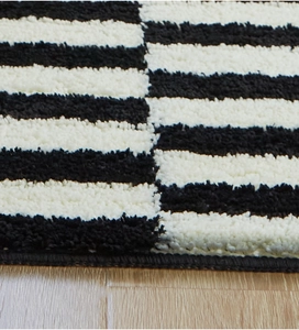 Macro shot of fluffy black and white striped plush carpet texture with stitched edges
