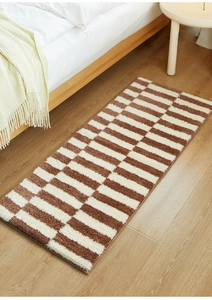 Detail of a brown and cream geometric bedside rug on a light wooden floor for cozy bedrooms
