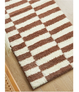 Close-up of thick tufted striped carpet texture on light wooden floor in bedroom