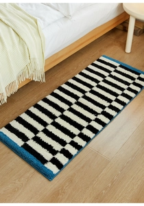 Detail of plush geometric striped bedside rug showing thick texture on wooden floor