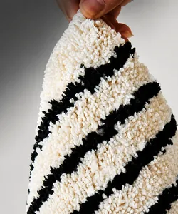 Primer plano de alfombra de baño de rayas blancas y negras mostrando fibras resistentes