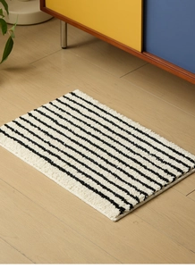Primer plano de la alfombra de baño a rayas blancas y negras sobre suelo de madera