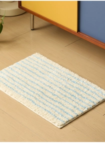 Detalle de rayas azules onduladas en alfombra de baño suave sobre suelo de madera