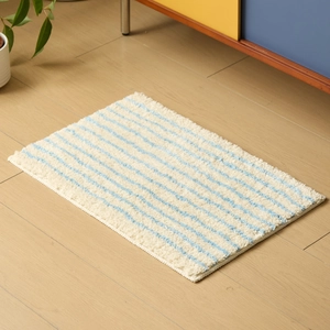 Alfombra de baño rectangular con ondas azules sobre fondo crema y textura suave