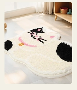 Close-up of thick plush lucky cat bath mat on light wood floor with warm sunlight