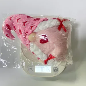 Close-up of pink Valentine's gnome plush with heart patterns on an electronic scale