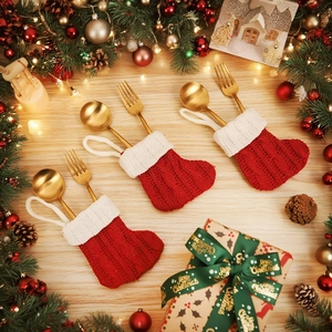 Dettaglio di calze di Natale in maglia rossa e bianca usate come portaposate per posate d'oro