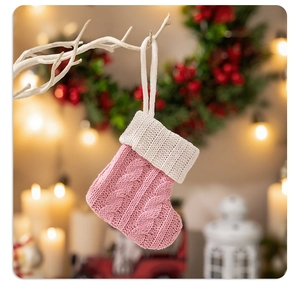 Dettaglio calza di Natale in maglia rosa con trama a trecce e gancio in lana bianca