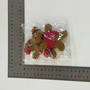 Detail view of plush gingerbread doll ornaments measured with a steel ruler for size