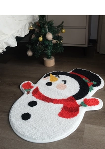 Detailed plush texture of a snowman shaped Christmas bath mat on a dark wood floor