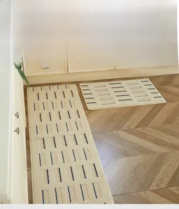 Detail of double-layer woven kitchen mat with textured stripes on herringbone wood floor