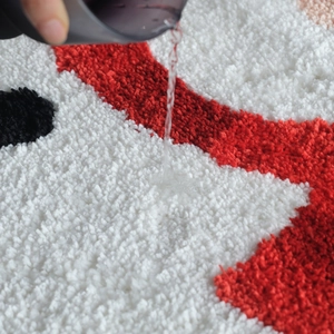 Christmas snowman bath mat with red and white plush fibers showing quick water absorption