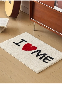 Vue détaillée du tapis de bain épais floqué avec motif I Heart ME sur sol en bois