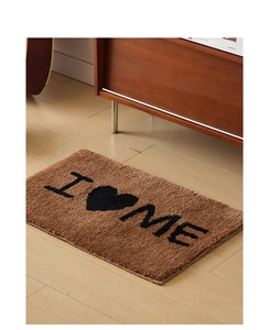 Détail du tapis de bain marron moelleux avec texte I Love Me et bords ourlés