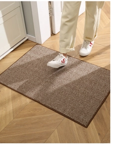 Detail view of woven doormat texture with brown stripes on wooden floor in home setting