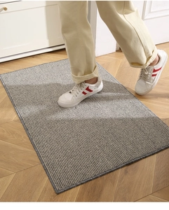Detail of gray striped anti-slip floor mat on wooden floor with casual sneakers