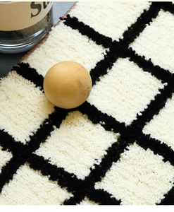 Detailed macro view of soft plush cream and black grid pattern shaggy texture rug