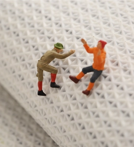 Close-up of miniature figure models with detailed painting on a white woven background