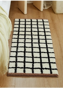 Close-up of Bauhaus checkered rug with soft tufted texture and brown plush edging