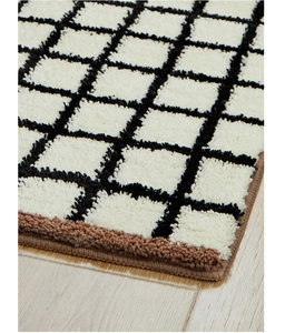 Close-up of black and white checkered tufted rug texture with durable brown stitched edges