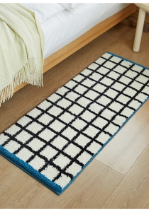 Detail shot of the plush black and white checkered carpet with soft texture and blue borders