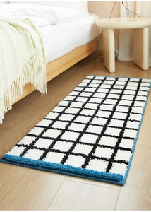 Close-up of thick checkered plush rug with blue stitched edges on light wood floor