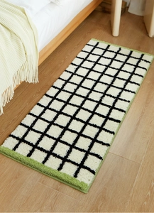 Close-up of black and white checkered plush rug with green accents on wooden floor