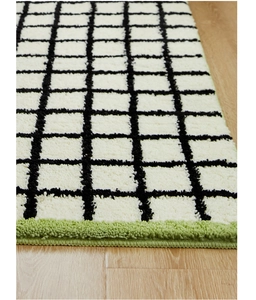 Macro detail of plush checkered rug with vibrant green stitched edges on wooden floor
