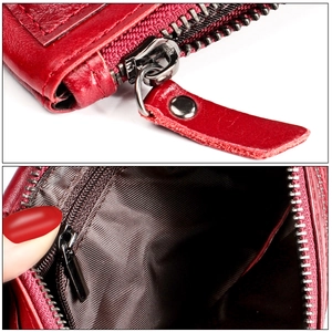 Detail of red pebbled leather wallet featuring silver zipper and striped fabric lining