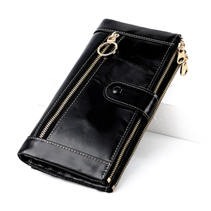 Detail of black glossy leather wallet showing dual zippers and golden ring ornament