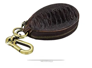 Detail of vintage brown leather car key case with ostrich texture and brass hook