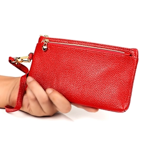 Dettaglio della pochette rossa in pelle a grana con ciondoli a cuore d'oro e doppia zip
