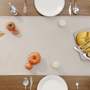 Overhead view of a linen table runner with pumpkins and candles for Thanksgiving decor