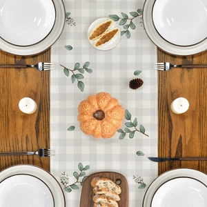 Linen table runner with eucalyptus leaf and berry pattern on a rustic wooden dining table